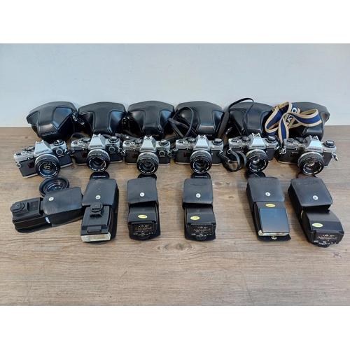 696 - Six cased Olympus OM10 35mm SLR cameras fitted with Zuiko 1:1.8 50mm lenses with cased T20 flashes