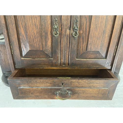 32 - An Arts & Crafts oak wall hanging two door smoker's cabinet - approx. 70cm high x 68cm wide