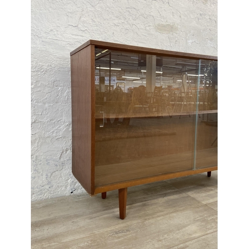 42 - A mid 20th century Avalon teak bookcase with two glass sliding doors - approx. 76cm high x 114cm wid... 