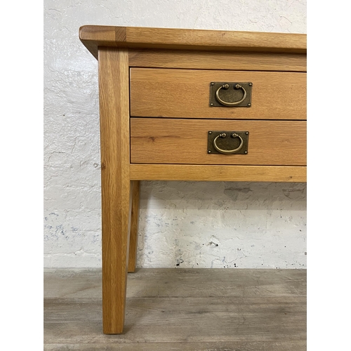 42A - A modern oak four drawer console table - approx. 75cm high x 120cm wide x 40cm deep