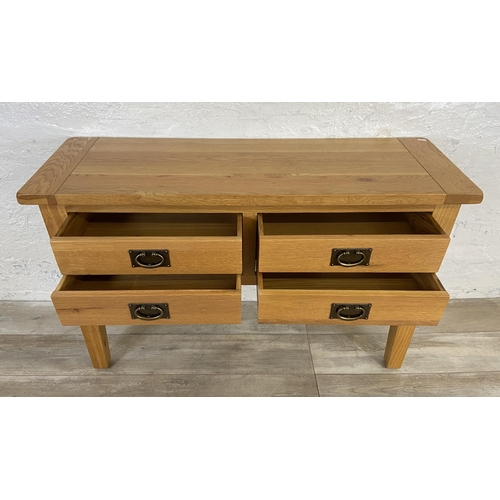 42A - A modern oak four drawer console table - approx. 75cm high x 120cm wide x 40cm deep