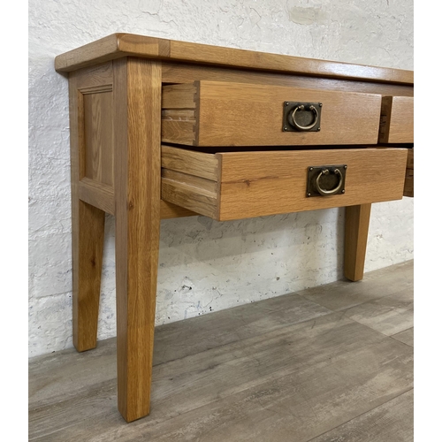 42A - A modern oak four drawer console table - approx. 75cm high x 120cm wide x 40cm deep