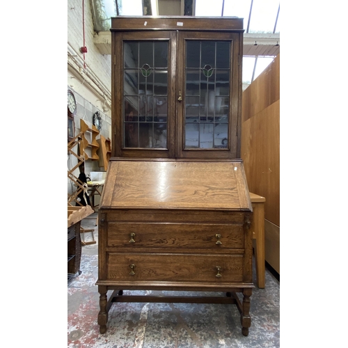 42B - An early 20th century oak bureau bookcase with two stained and leaded glass doors - approx. 198cm hi... 