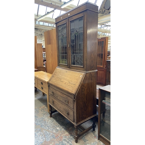 42B - An early 20th century oak bureau bookcase with two stained and leaded glass doors - approx. 198cm hi... 