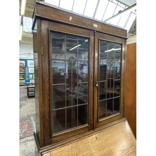 42B - An early 20th century oak bureau bookcase with two stained and leaded glass doors - approx. 198cm hi... 