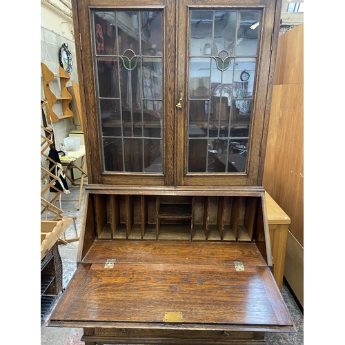 42B - An early 20th century oak bureau bookcase with two stained and leaded glass doors - approx. 198cm hi... 