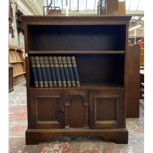 42D - A carved oak two tier bookcase containing Ten Volumes of The New Book of Knowledge - 103cm high x 84... 