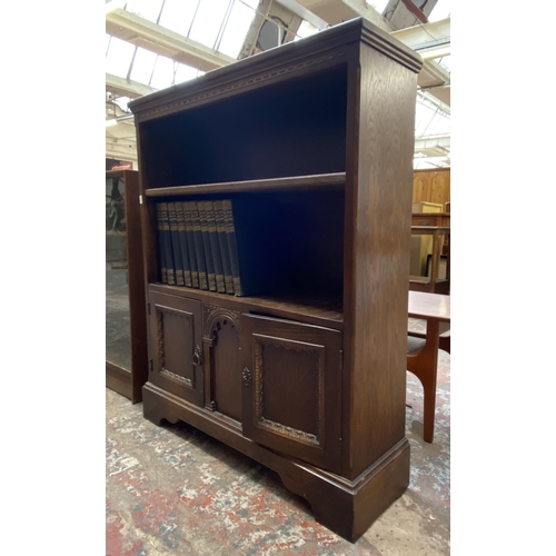 42D - A carved oak two tier bookcase containing Ten Volumes of The New Book of Knowledge - 103cm high x 84... 