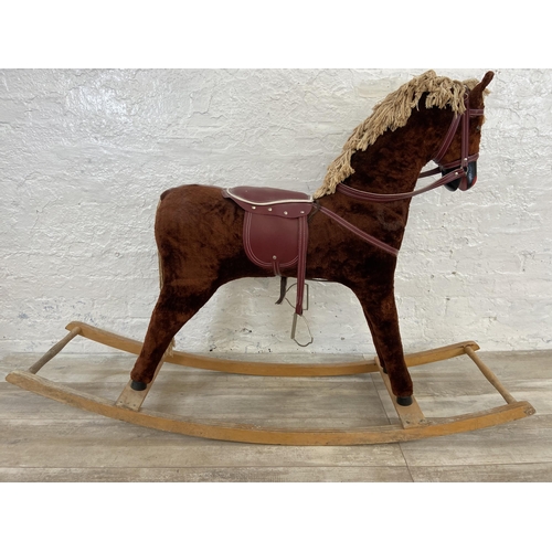 135 - A Victorian style brown fabric rocking horse with glass eyes on beech stand - approx. 100cm high x 3... 