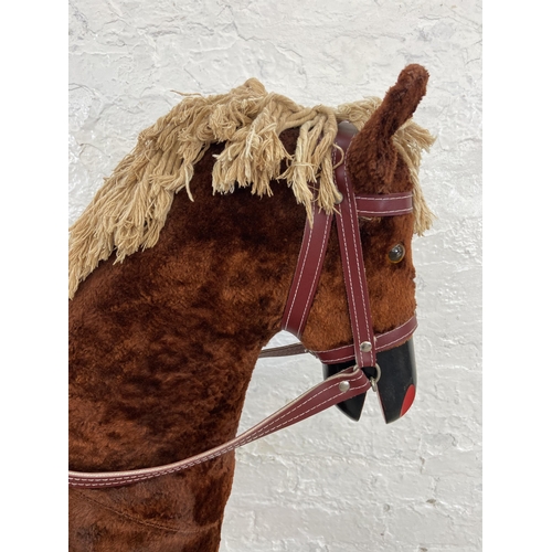 135 - A Victorian style brown fabric rocking horse with glass eyes on beech stand - approx. 100cm high x 3... 