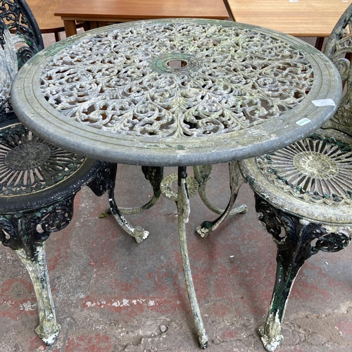 153 - A Victorian style cast metal three piece patio set comprising circular table and two chairs - table ... 