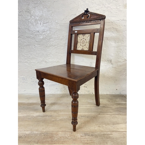 165 - Three 19th century carved hall chairs, two mahogany and one oak and mahogany with ceramic tile inser... 