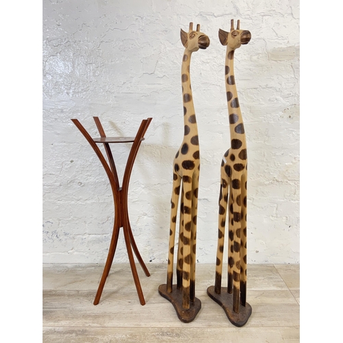 178 - Three items, two carved hardwood giraffe statues - approx. 101cm high and one Ron Lyons wooden jardi... 