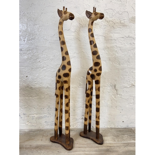 178 - Three items, two carved hardwood giraffe statues - approx. 101cm high and one Ron Lyons wooden jardi... 