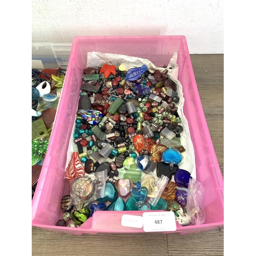 487 - Four boxes containing a large collection of glass pendants, charms and beads