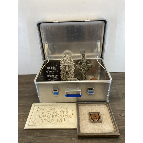 560 - An aluminium case containing a collection of cast stone wall plaques and signs