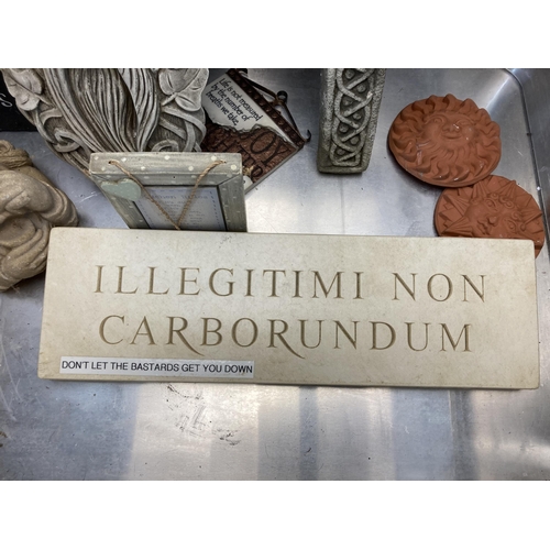 560 - An aluminium case containing a collection of cast stone wall plaques and signs