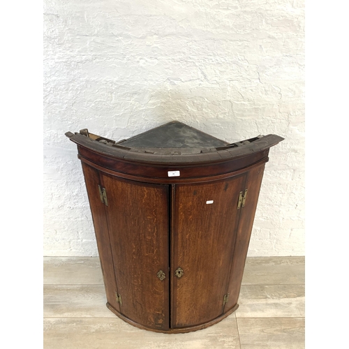 30 - A George III oak bow fronted wall hanging corner cabinet - approx. 106cm high x 74.5cm wide