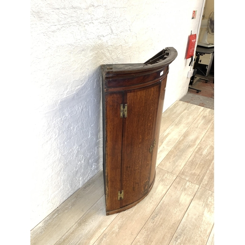 30 - A George III oak bow fronted wall hanging corner cabinet - approx. 106cm high x 74.5cm wide