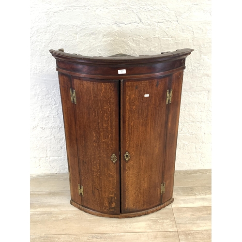 30 - A George III oak bow fronted wall hanging corner cabinet - approx. 106cm high x 74.5cm wide