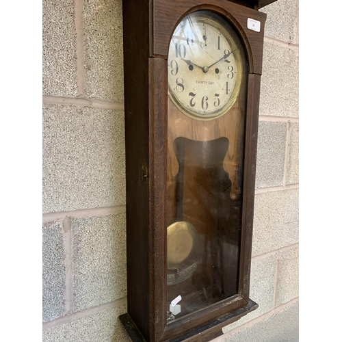 32 - A 1940s oak thirty day chiming wall clock - approx. 95cm high