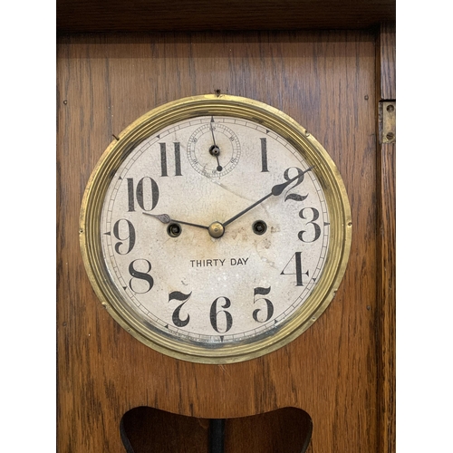 32 - A 1940s oak thirty day chiming wall clock - approx. 95cm high