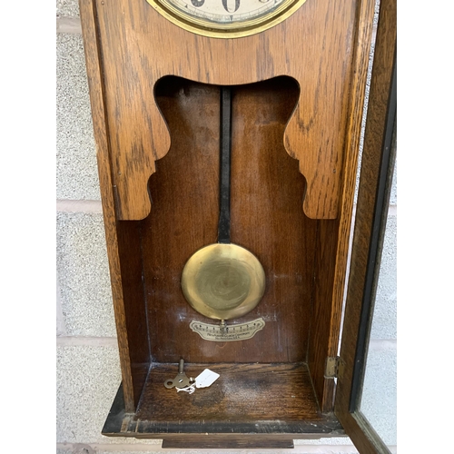 32 - A 1940s oak thirty day chiming wall clock - approx. 95cm high