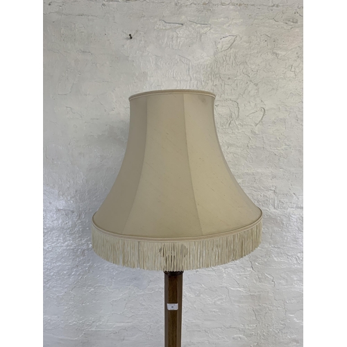 39 - A 20th century mahogany tapered standard lamp with white tasseled shade - approx. 160cm high (exclud... 