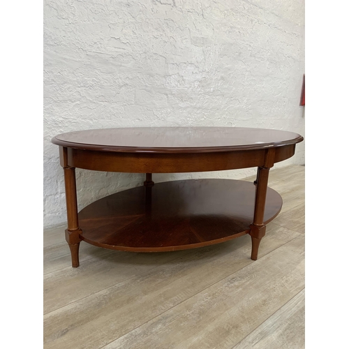 63 - A late 20th century mahogany oval two tier coffee table