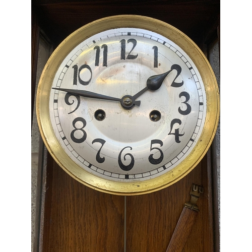 26 - An early 20th century oak cased chiming wall clock with pendulum and key - approx. 88cm high x 31cm ... 