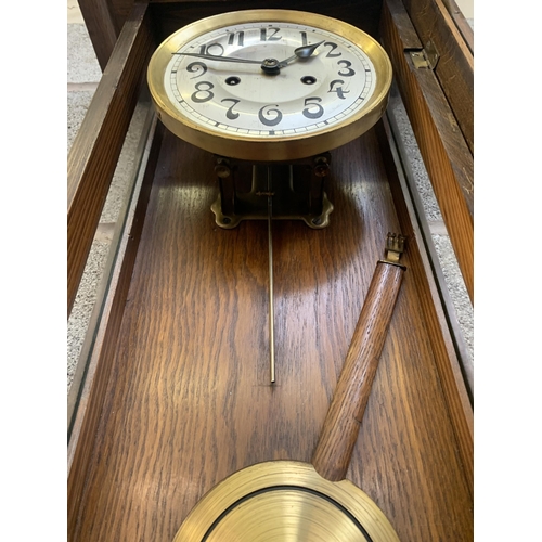 26 - An early 20th century oak cased chiming wall clock with pendulum and key - approx. 88cm high x 31cm ... 