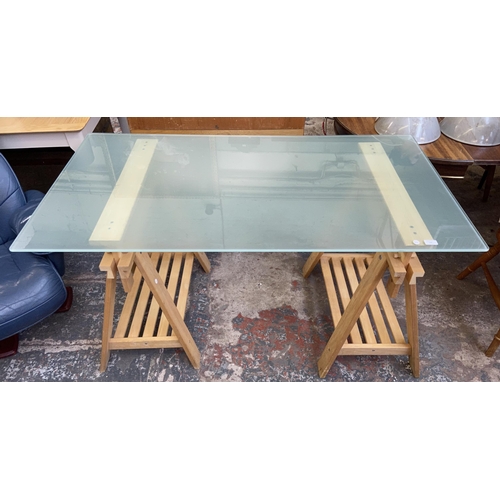 108 - An IKEA glass top desk on beech trestle supports - approx. 82cm high x 149cm wide x 79cm deep