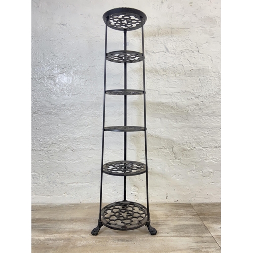 46 - A Victorian style black painted cast metal six tier pan stand on lion paw feet - approx. 123cm high