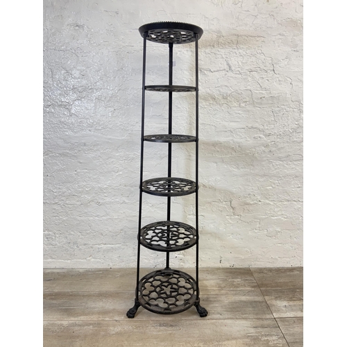 46 - A Victorian style black painted cast metal six tier pan stand on lion paw feet - approx. 123cm high