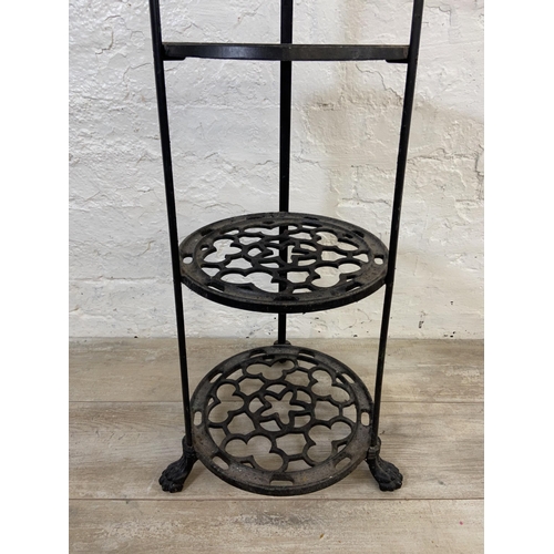 46 - A Victorian style black painted cast metal six tier pan stand on lion paw feet - approx. 123cm high