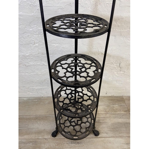 46 - A Victorian style black painted cast metal six tier pan stand on lion paw feet - approx. 123cm high