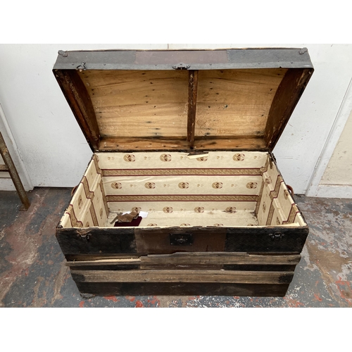 55 - An early 20th century dome top travel trunk with wooden and metal banding