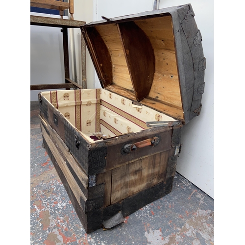 55 - An early 20th century dome top travel trunk with wooden and metal banding