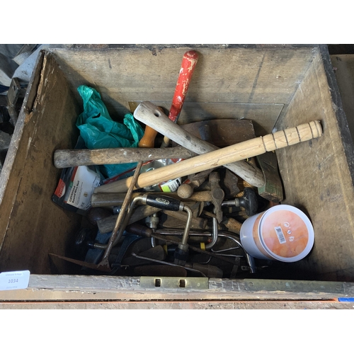 1034 - A vintage wooden tool chest containing various hand tools to include hammers, clamps, spanners etc.