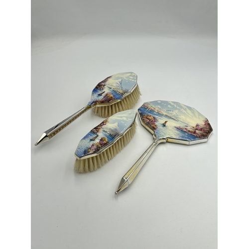 2165 - A cased Art Deco hand painted enamel and white metal three piece dressing table set