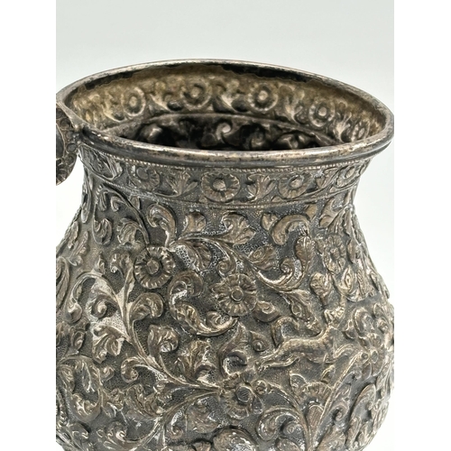 2159 - A late 19th century Indian white metal tankard with repoussé foliate and animal design and engraved ... 