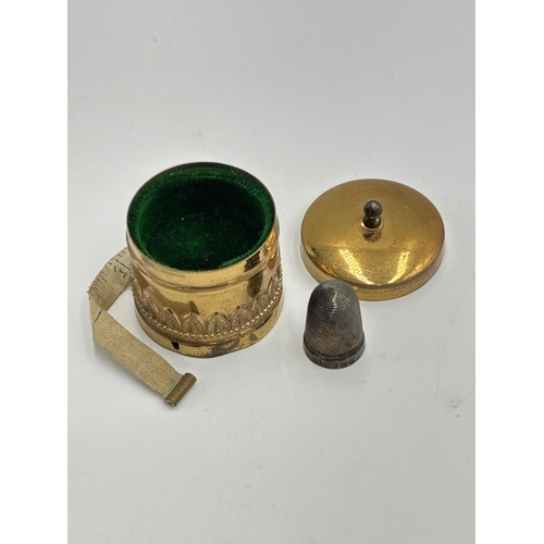 2223 - Two sewing accessories, one Victorian brass thimble holder with tape measure and one hallmarked Ches... 