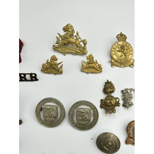 2292 - A collection of military cap badges, shoulder titles and buttons to include Kenya Police, British So... 