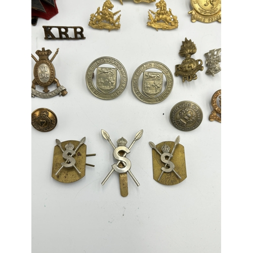 2292 - A collection of military cap badges, shoulder titles and buttons to include Kenya Police, British So... 