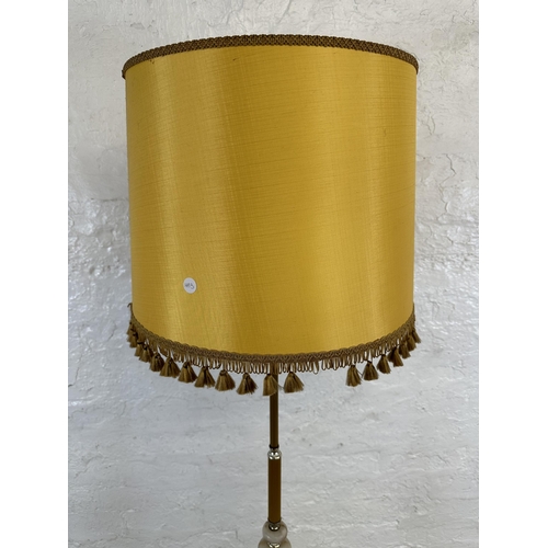 25 - A mid 20th century onyx and brass standard lamp with yellow tasselled shade - approx. 155cm high inc... 