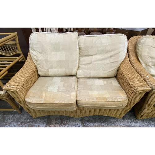 104 - A wicker four piece conservatory suite comprising two seater sofa, two armchairs and side table