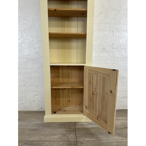 186 - A modern pine and cream painted four tier bookcase with cupboard door - approx. 197cm high x 66cm wi... 