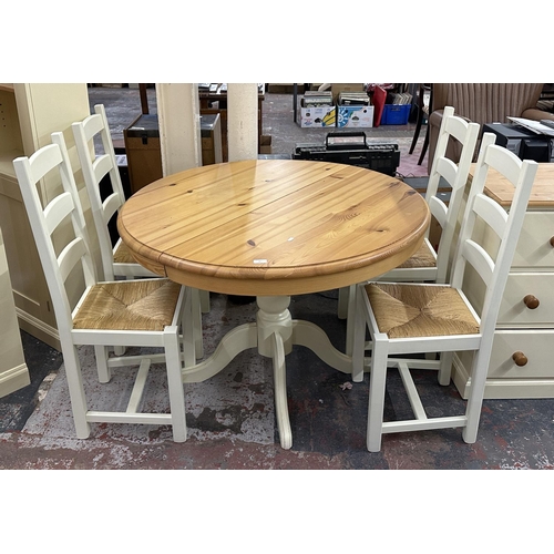 187 - A modern pine and cream painted circular extending dining table and four white painted and rush seat... 