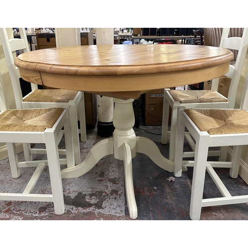 187 - A modern pine and cream painted circular extending dining table and four white painted and rush seat... 