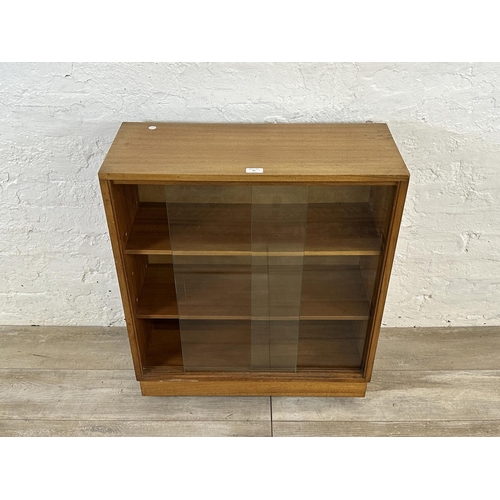 81 - A mid 20th century teak bookcase with two glass sliding doors - approx. 81cm high x 68cm wide x 28cm... 